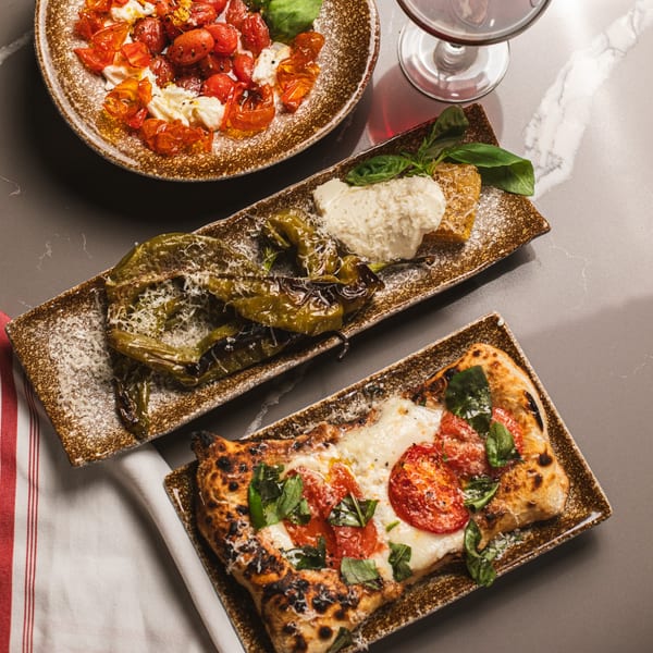 Three Italian dishes: roasted tomatoes with cheese, grilled peppers with cheese, and a rectangular pizza.